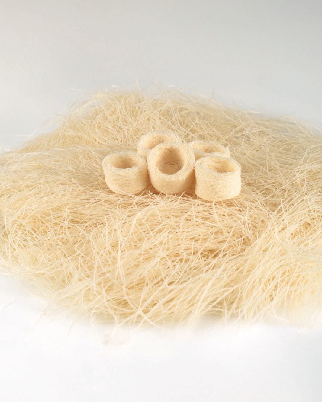 Four unbaked kadayif nests on a bed of white kadayif strands