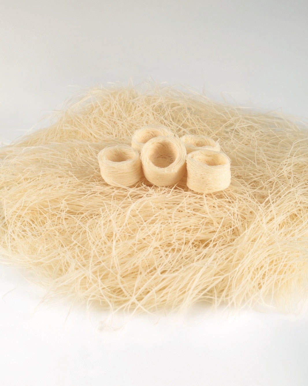 Four unbaked kadayif nests on a bed of white kadayif strands